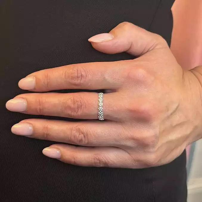 Hand wearing a silver ring with a black background