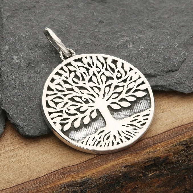 Silver tree of life pendant on a stone and wood background