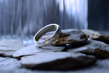 Close-up of a sterling silver ring with a patterned, hammered design. The 5mm wide band is crafted to order, ensuring no two rings are alike.