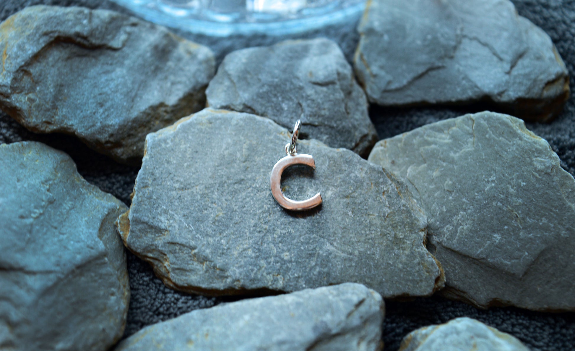 A delicate sterling silver pendant shaped like an initial, designed with a loop to fit small necklace chains.