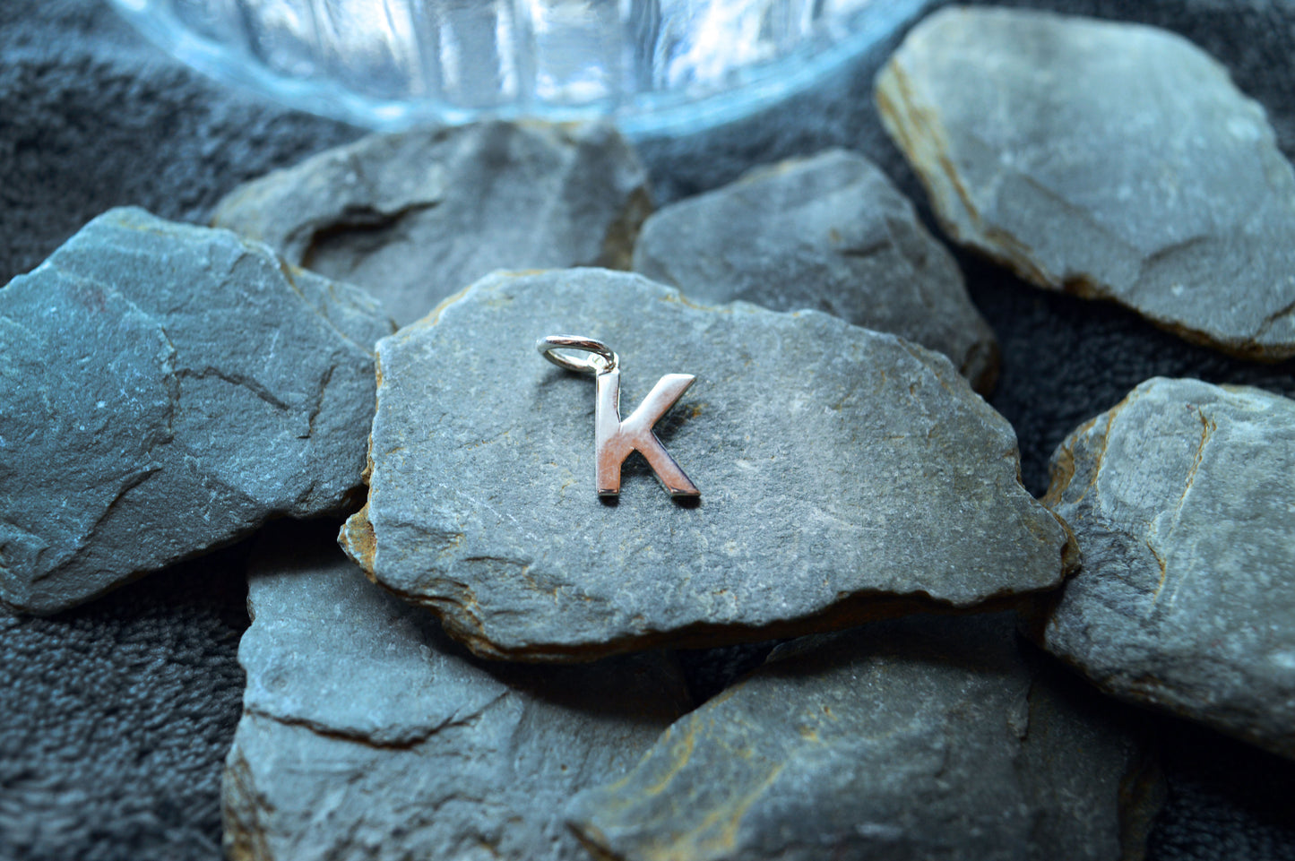 A simple and elegant sterling silver initial pendant with a pre-looped design for necklace customization.