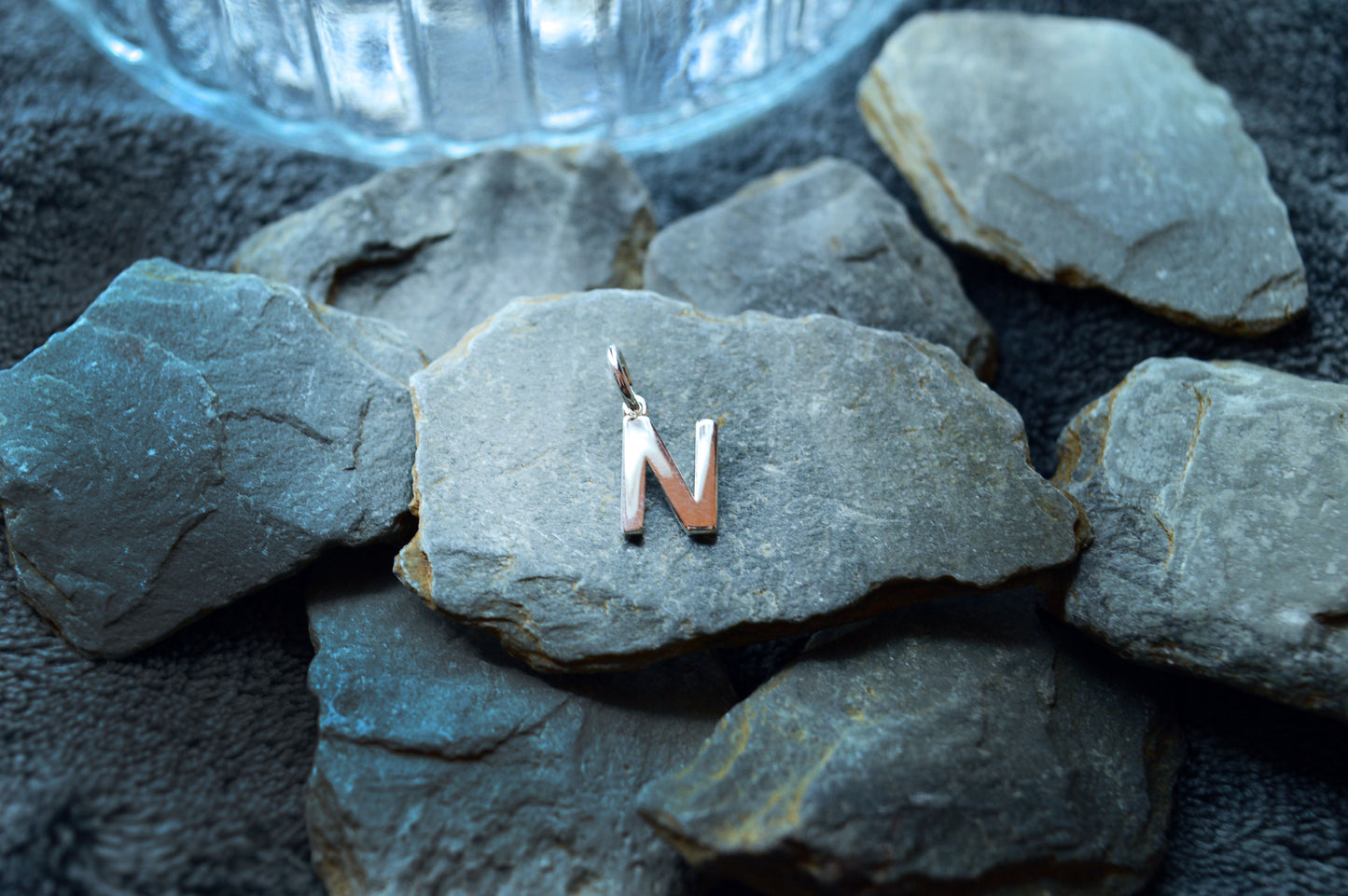 Delicate sterling silver initial pendant, measuring 10mm in height, 8mm in width, and 1.5mm thick.