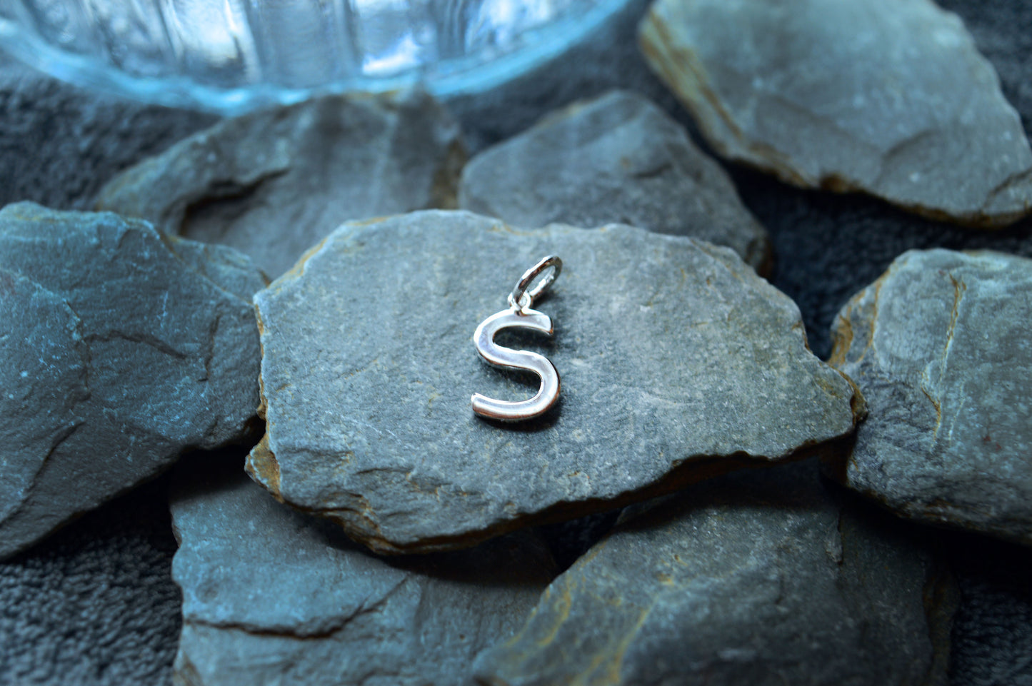 A polished silver initial pendant, 10mm high, featuring a pre-looped design to easily slide onto necklace chains.