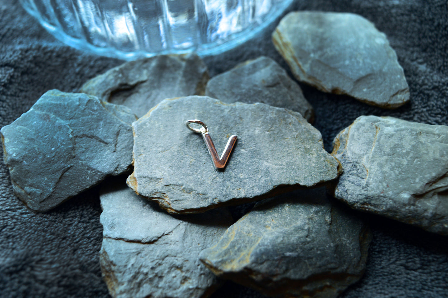 Close-up of a silver initial pendant with a smooth finish and pre-looped hole, perfect for personalized necklaces.