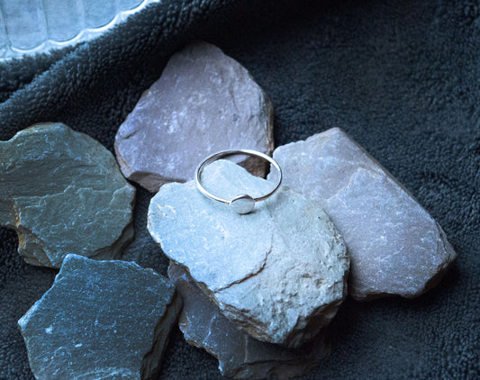 Close-up of a 925 sterling silver minimalist button ring with a 5mm flat circle focal point. The band width is approximately 1.5mm.